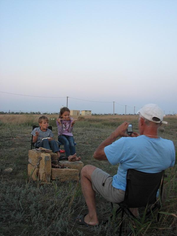 Verin papa fotografiruet kak Ksenya i Savva edyat shashlik v lagere na Belyause
