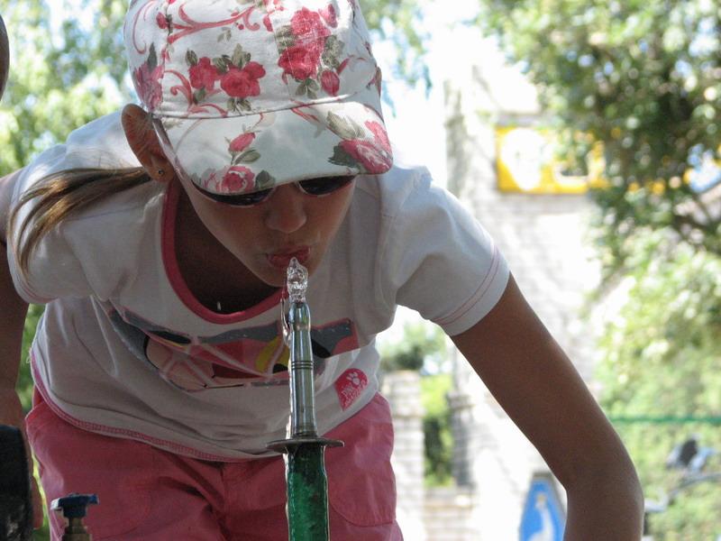 Ksenya piet iz kolonki s vodoj u vhoda v zoopark Askaniya-Nova